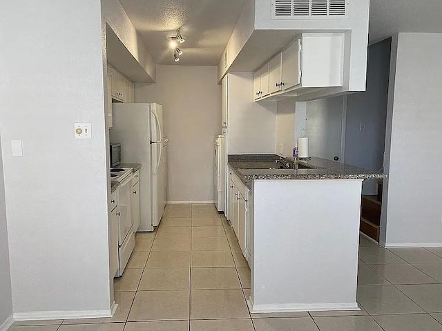 kitchen with light tile patterned floors, white cabinets, white appliances, and dark countertops