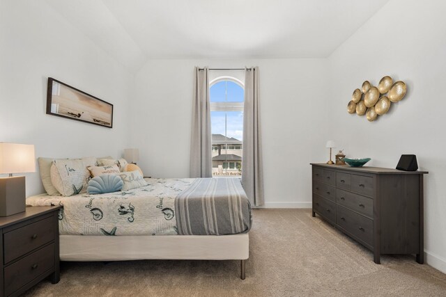 bedroom with light colored carpet, baseboards, and lofted ceiling