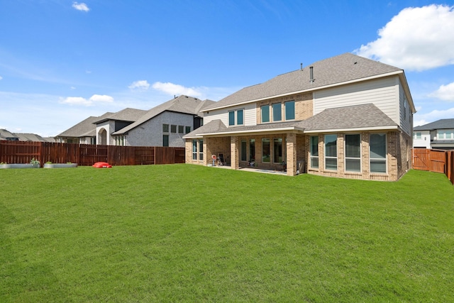 rear view of property with a lawn, a fenced backyard, and brick siding