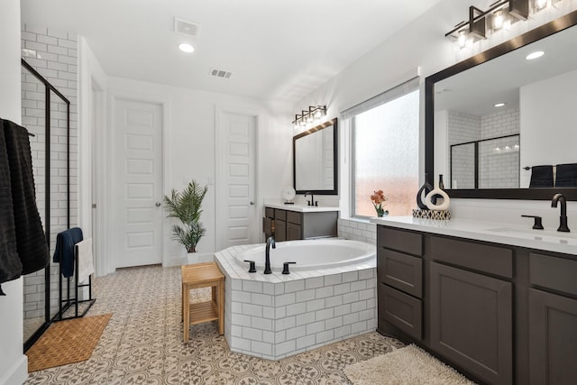 bathroom with a shower stall, a garden tub, visible vents, and a sink