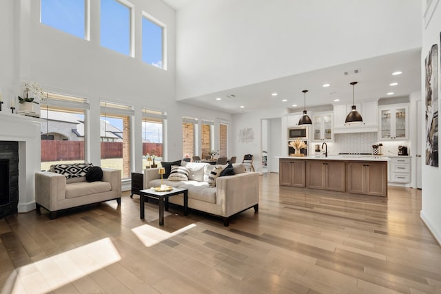 living room featuring visible vents, recessed lighting, a fireplace, and light wood-type flooring