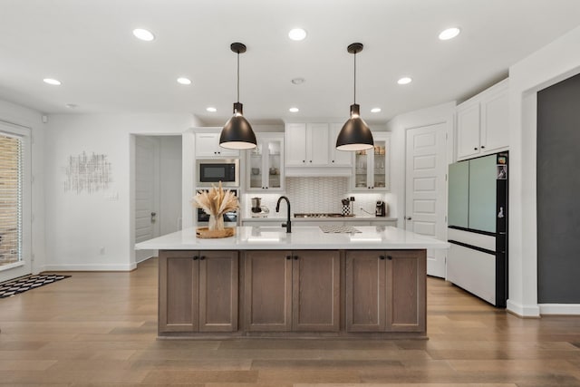 kitchen with stainless steel oven, built in microwave, light countertops, and freestanding refrigerator