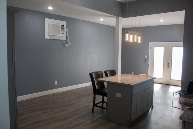 kitchen with a breakfast bar, a center island, french doors, baseboards, and dark wood-style flooring