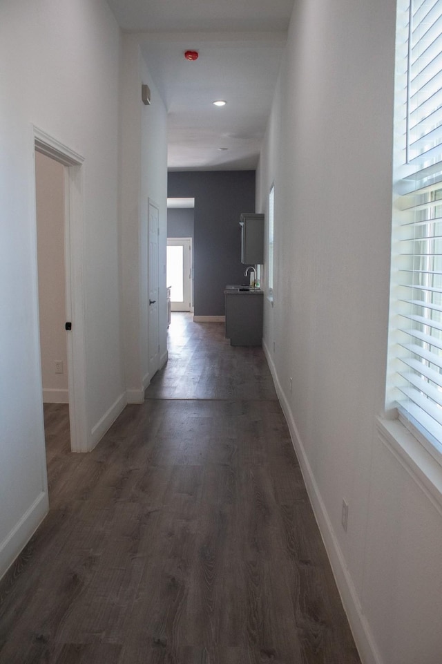 corridor with a sink, baseboards, and wood finished floors