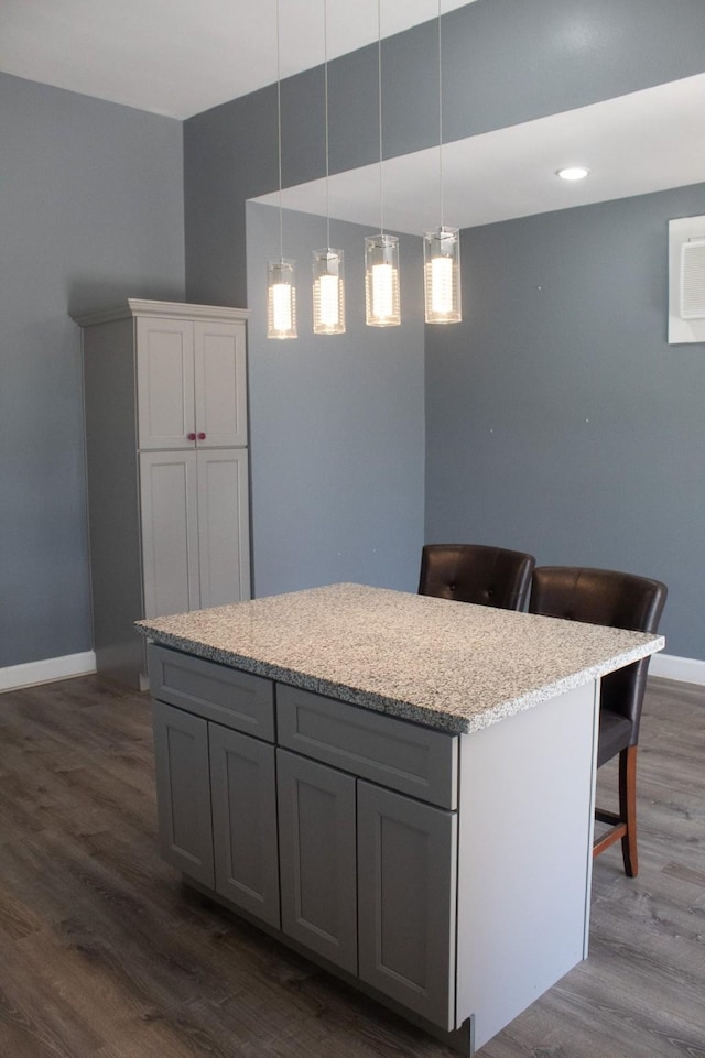 kitchen featuring dark wood-type flooring, decorative light fixtures, gray cabinets, and a center island