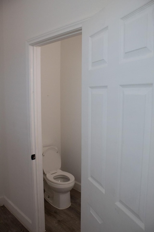 bathroom with toilet, baseboards, and wood finished floors