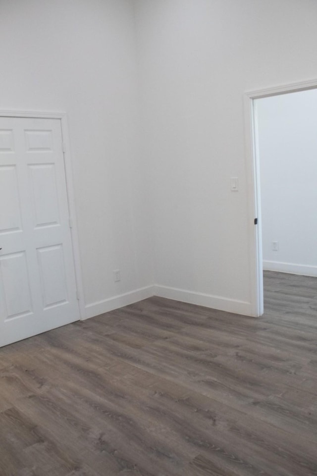 empty room with baseboards and dark wood-style flooring