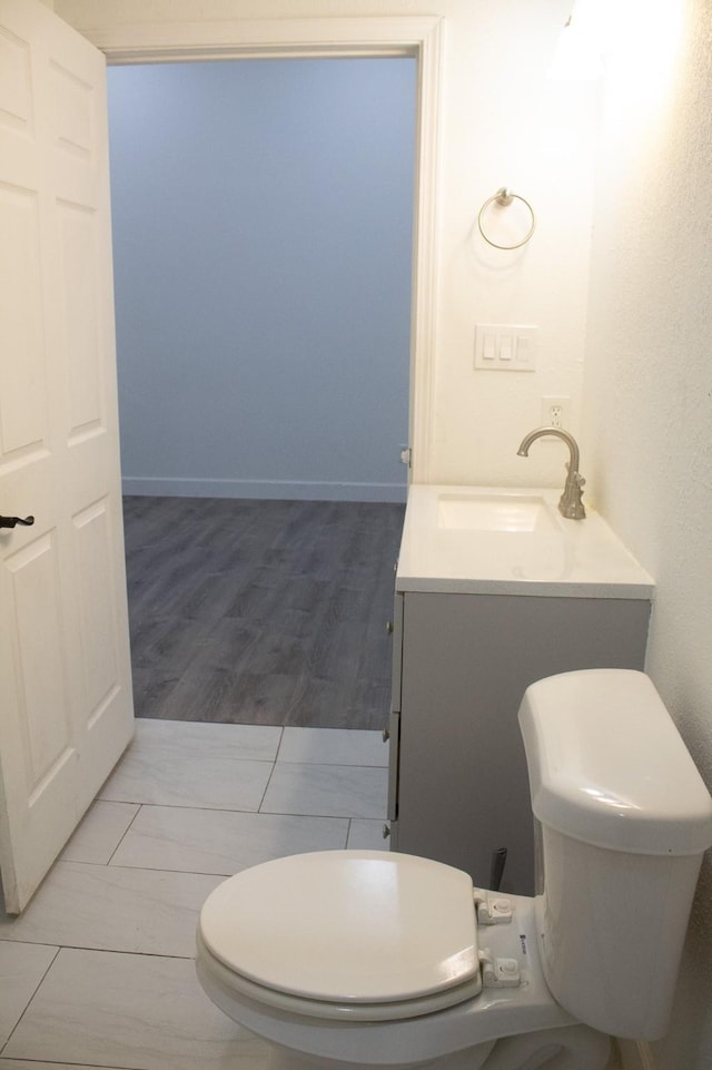 half bath featuring toilet, vanity, and wood finished floors