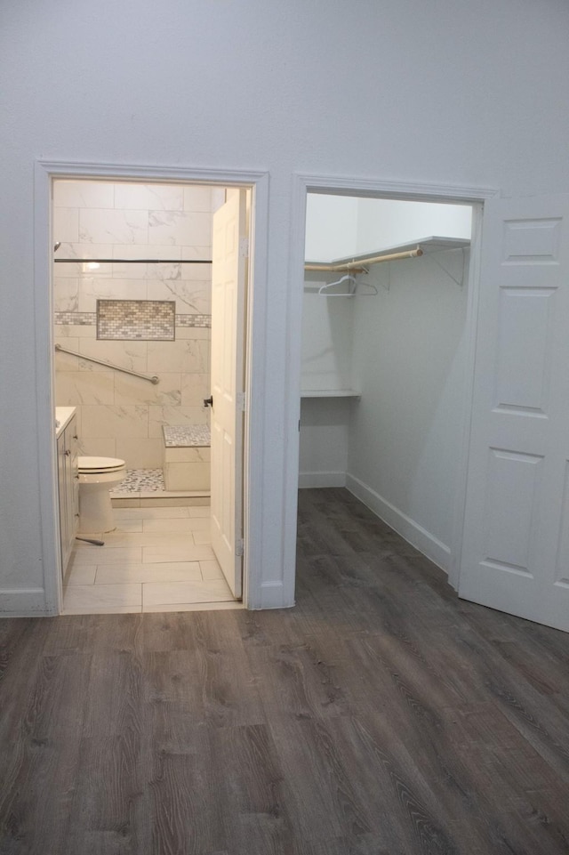 bathroom featuring vanity, toilet, wood finished floors, and a tile shower