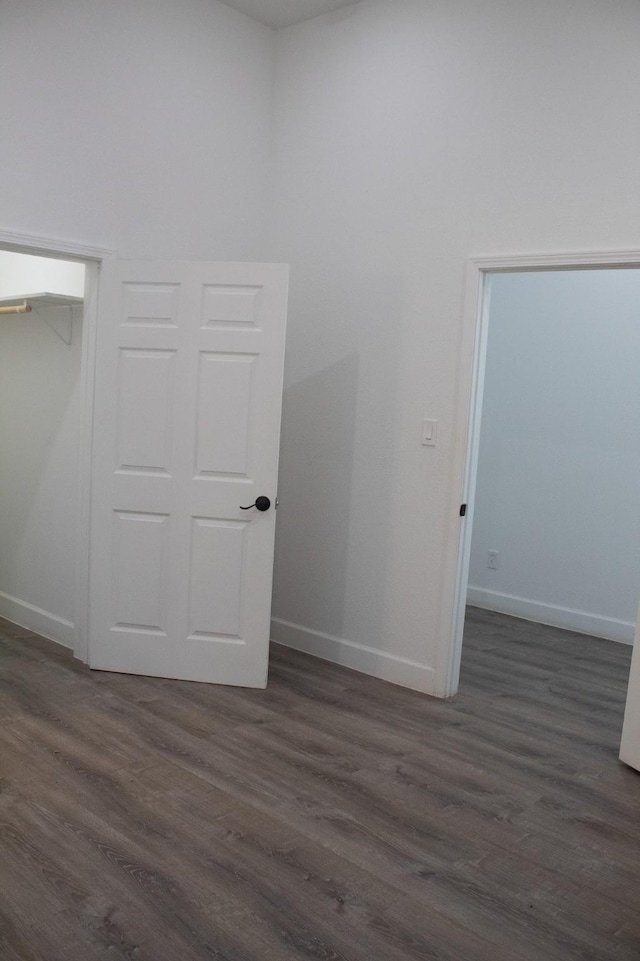 spare room featuring dark wood-style floors and baseboards