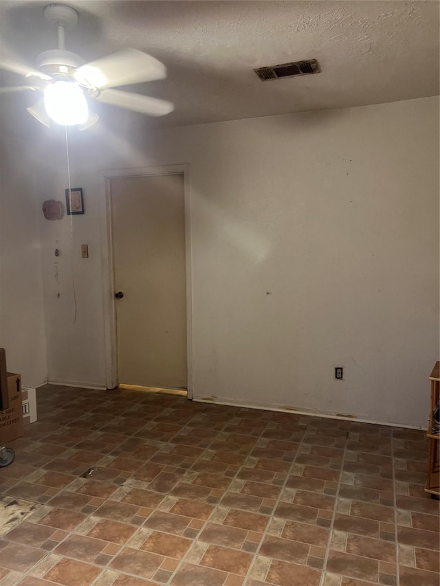 empty room with brick floor, visible vents, and ceiling fan