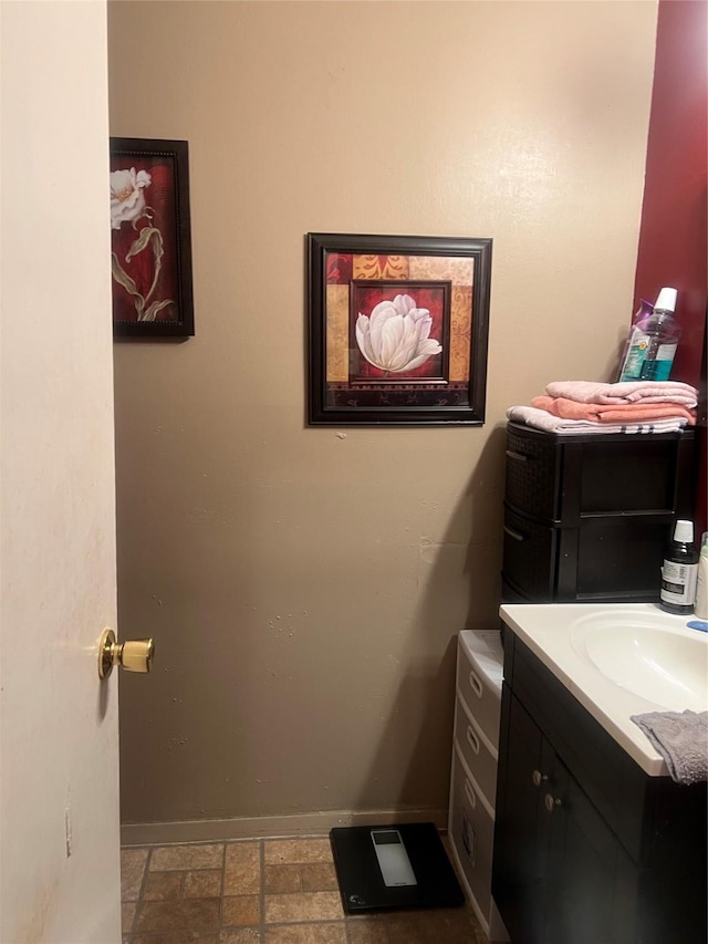 bathroom with vanity, baseboards, and stone finish flooring