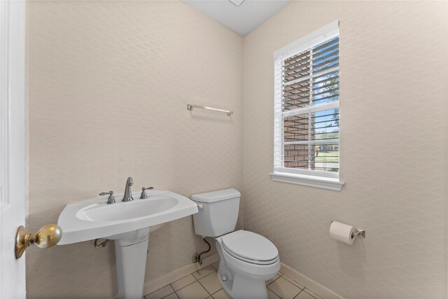 bathroom with tile patterned flooring, toilet, baseboards, and wallpapered walls