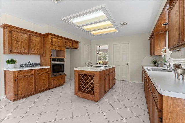 kitchen with visible vents, brown cabinets, oven, and a sink