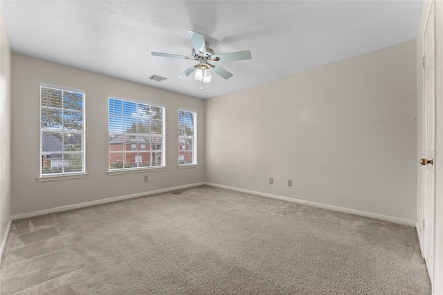 carpeted spare room with visible vents, baseboards, and a ceiling fan