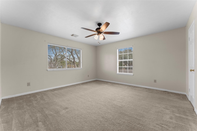 carpeted empty room with visible vents, plenty of natural light, baseboards, and ceiling fan