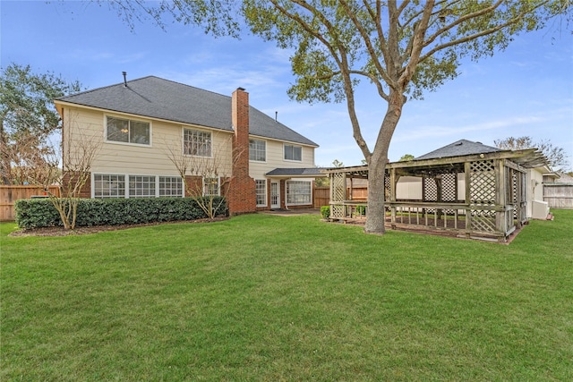 rear view of house with a lawn, a chimney, and fence