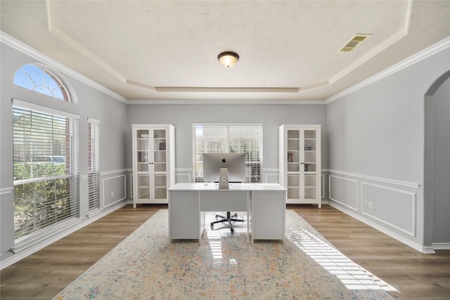 office with wood finished floors, a tray ceiling, arched walkways, french doors, and a decorative wall