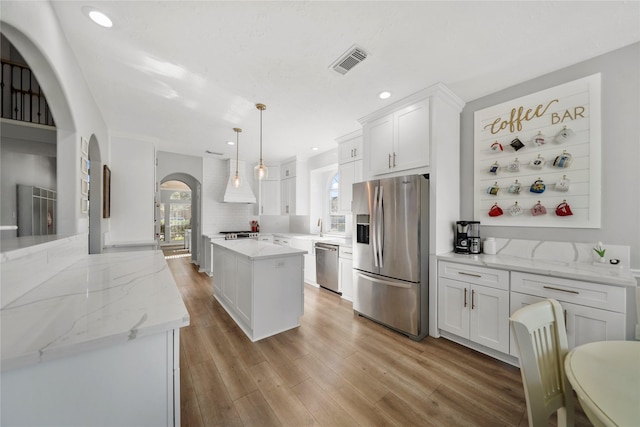 kitchen with a wealth of natural light, stainless steel appliances, arched walkways, and visible vents