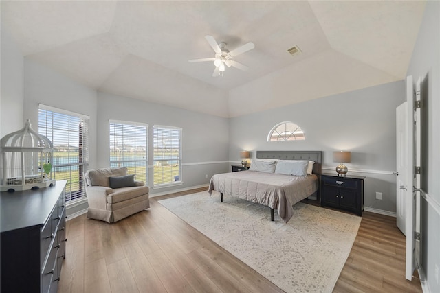 bedroom with vaulted ceiling, wood finished floors, visible vents, and baseboards