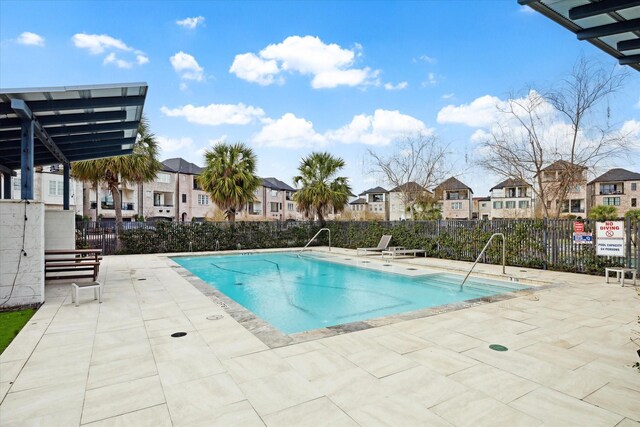 pool with a patio area, fence, and a residential view