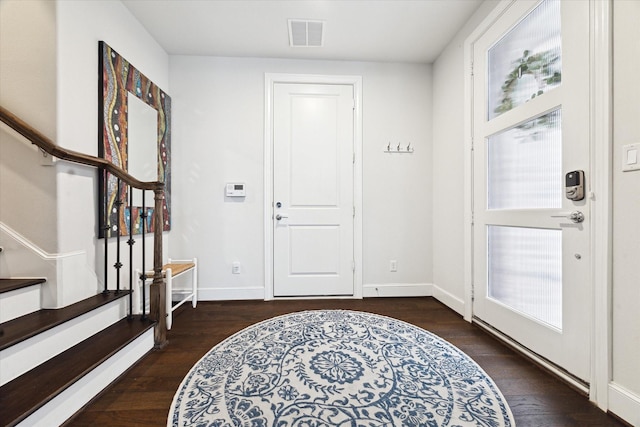 foyer entrance featuring visible vents, baseboards, wood finished floors, and stairway