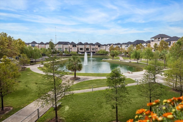 view of property's community with a yard, fence, a residential view, and a water view