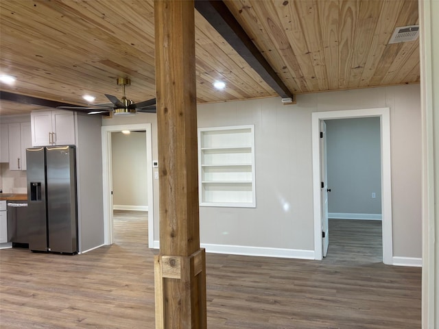 interior space with built in shelves, wood finished floors, baseboards, wood ceiling, and stainless steel fridge