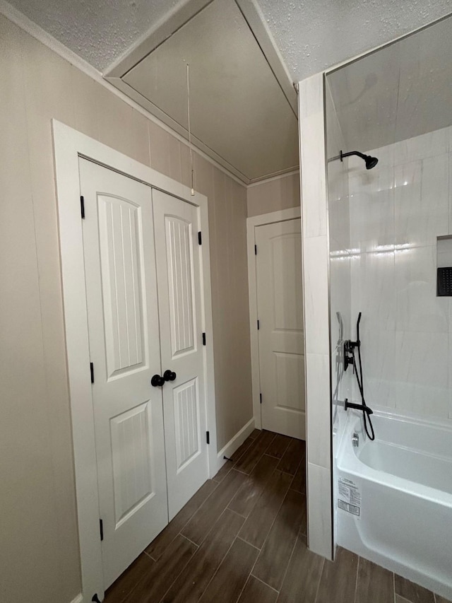 bathroom with baseboards, a textured ceiling, crown molding,  shower combination, and wood finish floors
