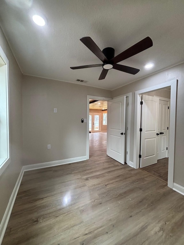 spare room with visible vents, baseboards, a ceiling fan, and wood finished floors