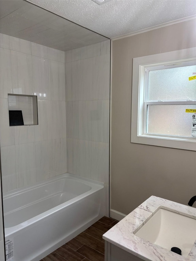 full bathroom featuring bathtub / shower combination, wood finish floors, a textured ceiling, vanity, and ornamental molding