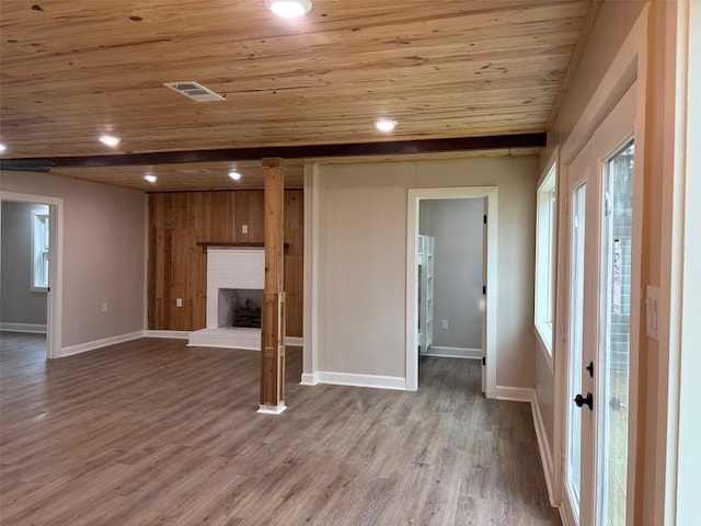 unfurnished living room with visible vents, wood ceiling, baseboards, and wood finished floors