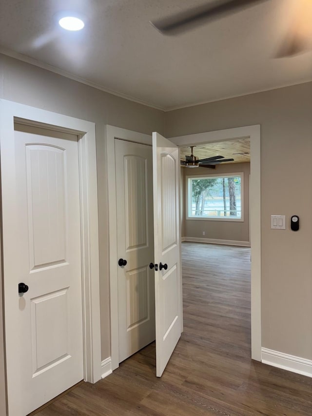 hall with crown molding, baseboards, and dark wood-style flooring