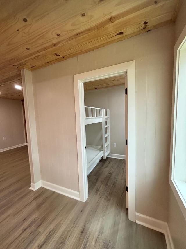 hallway with baseboards, wooden ceiling, and wood finished floors