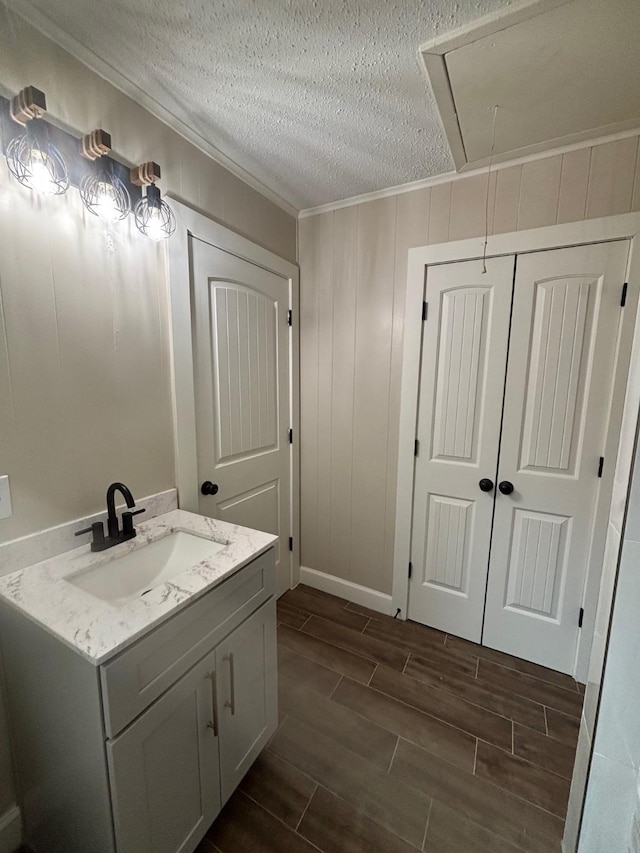 bathroom featuring ornamental molding, a textured ceiling, vanity, and wood tiled floor