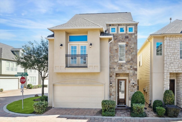 view of front of home with a balcony, a shingled roof, stucco siding, stone siding, and decorative driveway