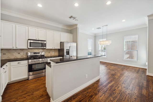 kitchen featuring dark countertops, dark wood-style floors, appliances with stainless steel finishes, and a center island