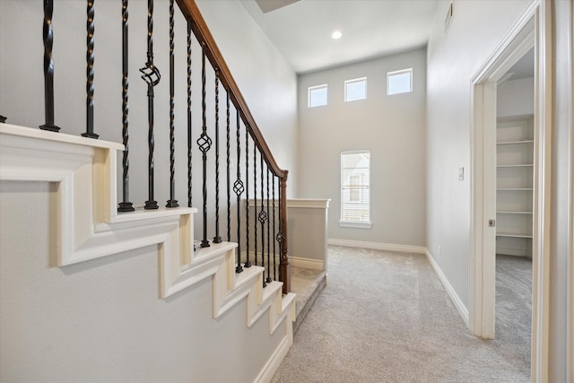 stairs featuring recessed lighting, baseboards, a towering ceiling, and carpet flooring