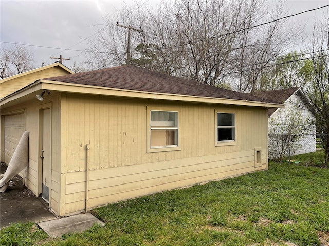 view of side of home featuring a yard, roof with shingles, and fence