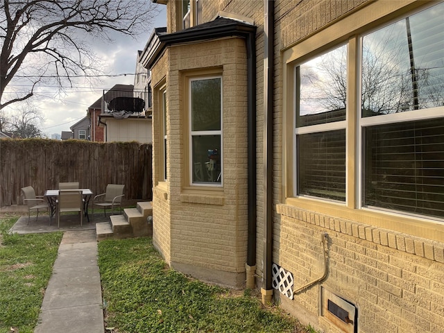 view of property exterior with a patio, cooling unit, fence, and brick siding