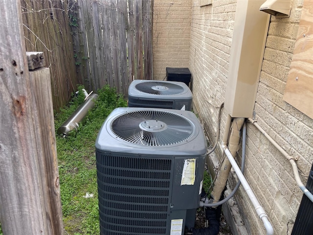 exterior details featuring fence, central AC unit, and brick siding