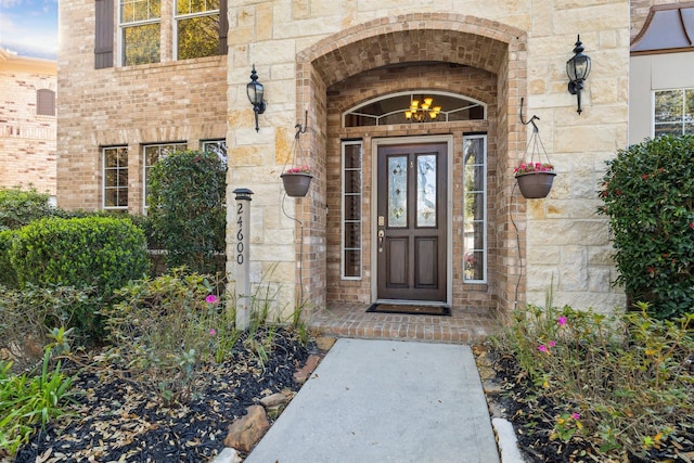 view of exterior entry featuring brick siding and stone siding