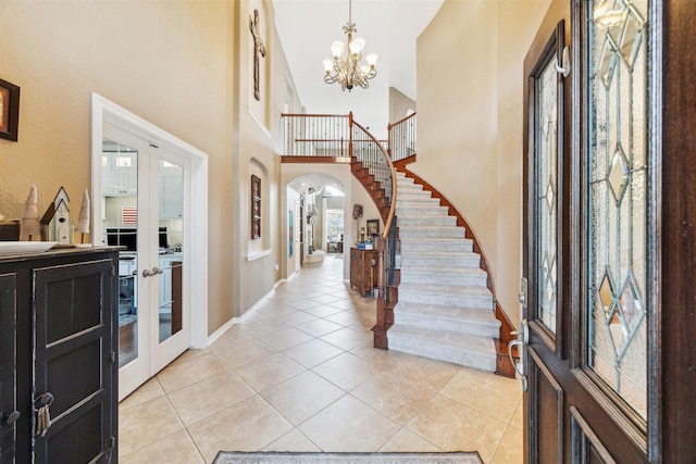 foyer with light tile patterned floors, french doors, and arched walkways