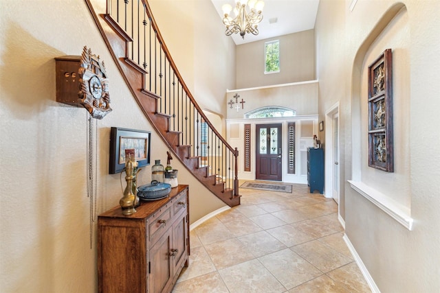 entryway with stairway, a high ceiling, light tile patterned flooring, baseboards, and a chandelier