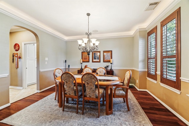 dining room with visible vents, wood finished floors, arched walkways, baseboards, and a chandelier