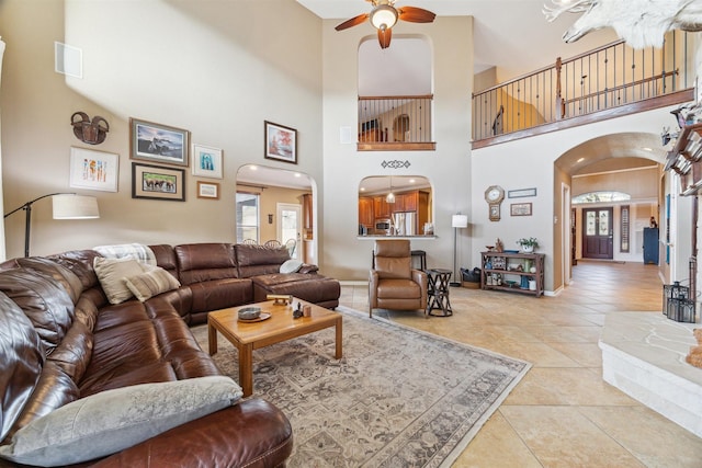 living area with arched walkways, visible vents, baseboards, and light tile patterned flooring