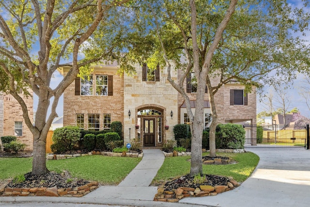 view of front of house featuring brick siding, fence, concrete driveway, a front yard, and stone siding