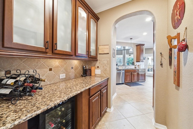 kitchen with beverage cooler, light stone countertops, arched walkways, stainless steel dishwasher, and tasteful backsplash