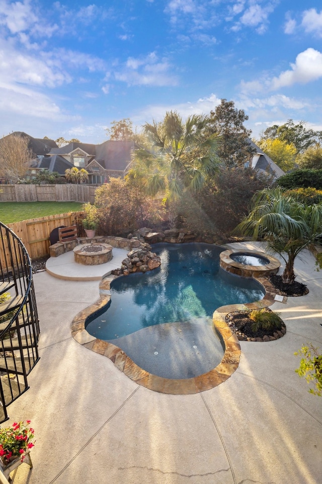 view of pool with a patio area, a pool with connected hot tub, a fire pit, and fence