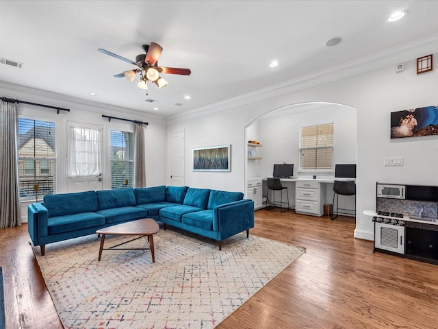 living area with visible vents, ornamental molding, recessed lighting, wood finished floors, and arched walkways